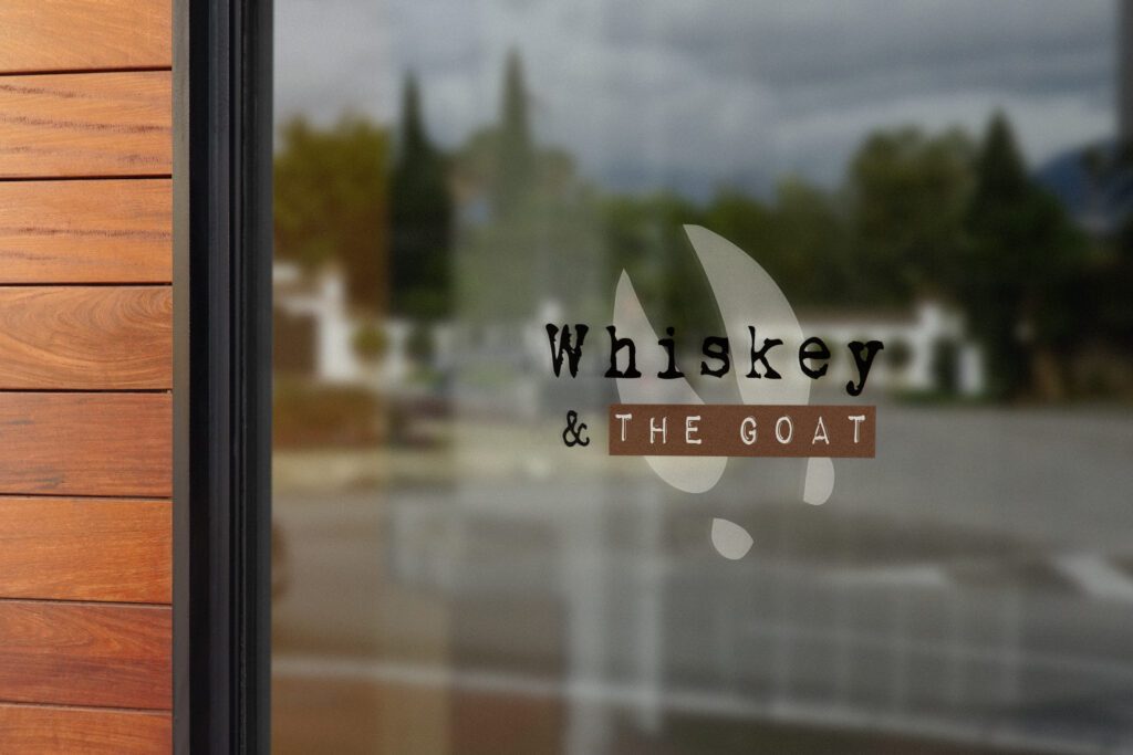 Window logo of Whiskey & the Goat, showcasing effective restaurant branding that beckons patrons into the inviting bar space.